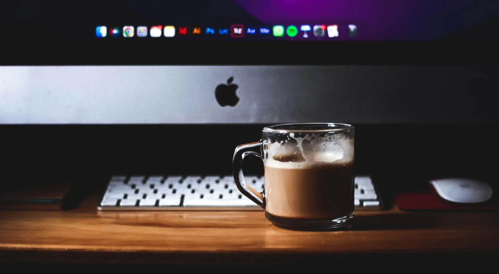 O cană de cafea în fața unui calculator, la birou